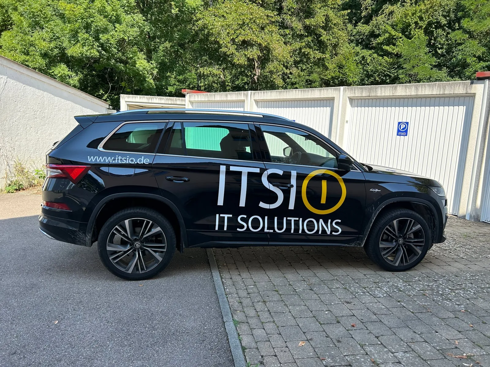 Firmenwagen von ITSIO mit Logo vor den Garagen