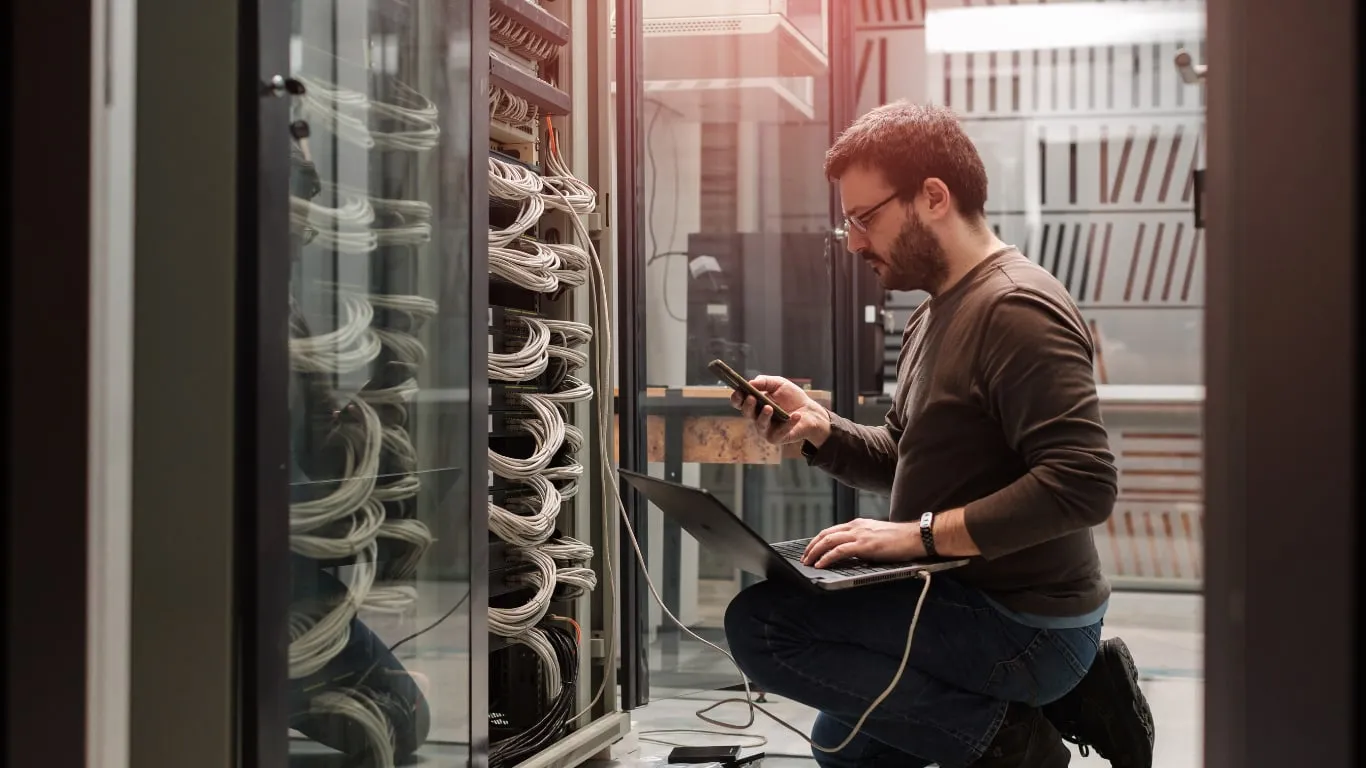 Techniker mit Notebook vor einem Serverschrank im Rechenzentrum