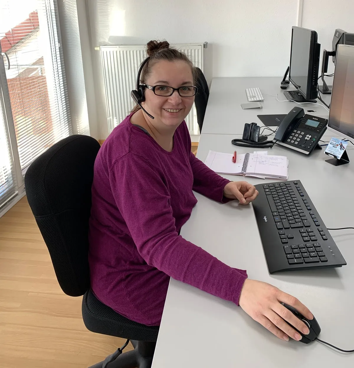 Mitarbeiterin von ITSIO mit Headset an ihrem Arbeitsplatz